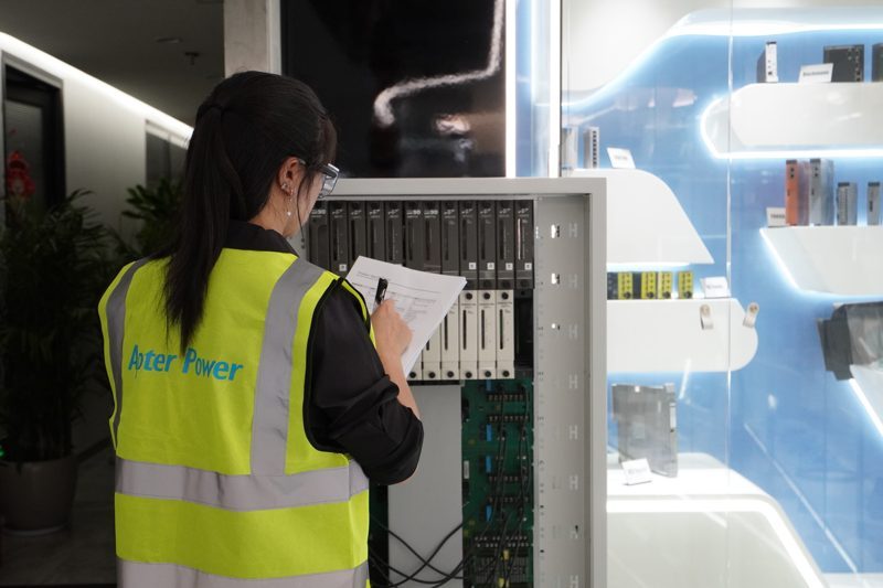 Technician recording an industrial control rack inspection